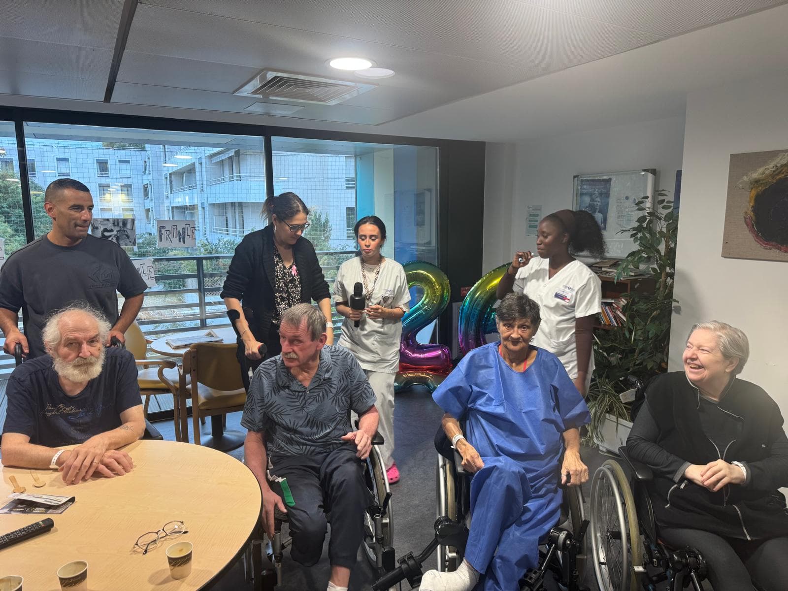 Visiteurs et patients autour de la table, avec un ballon.