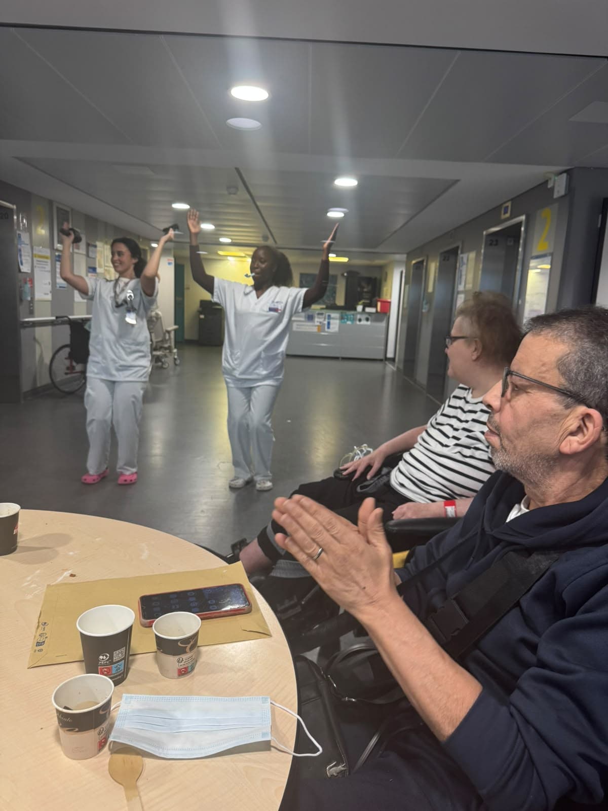 Les bénévoles dansent devant une patiente attablée.